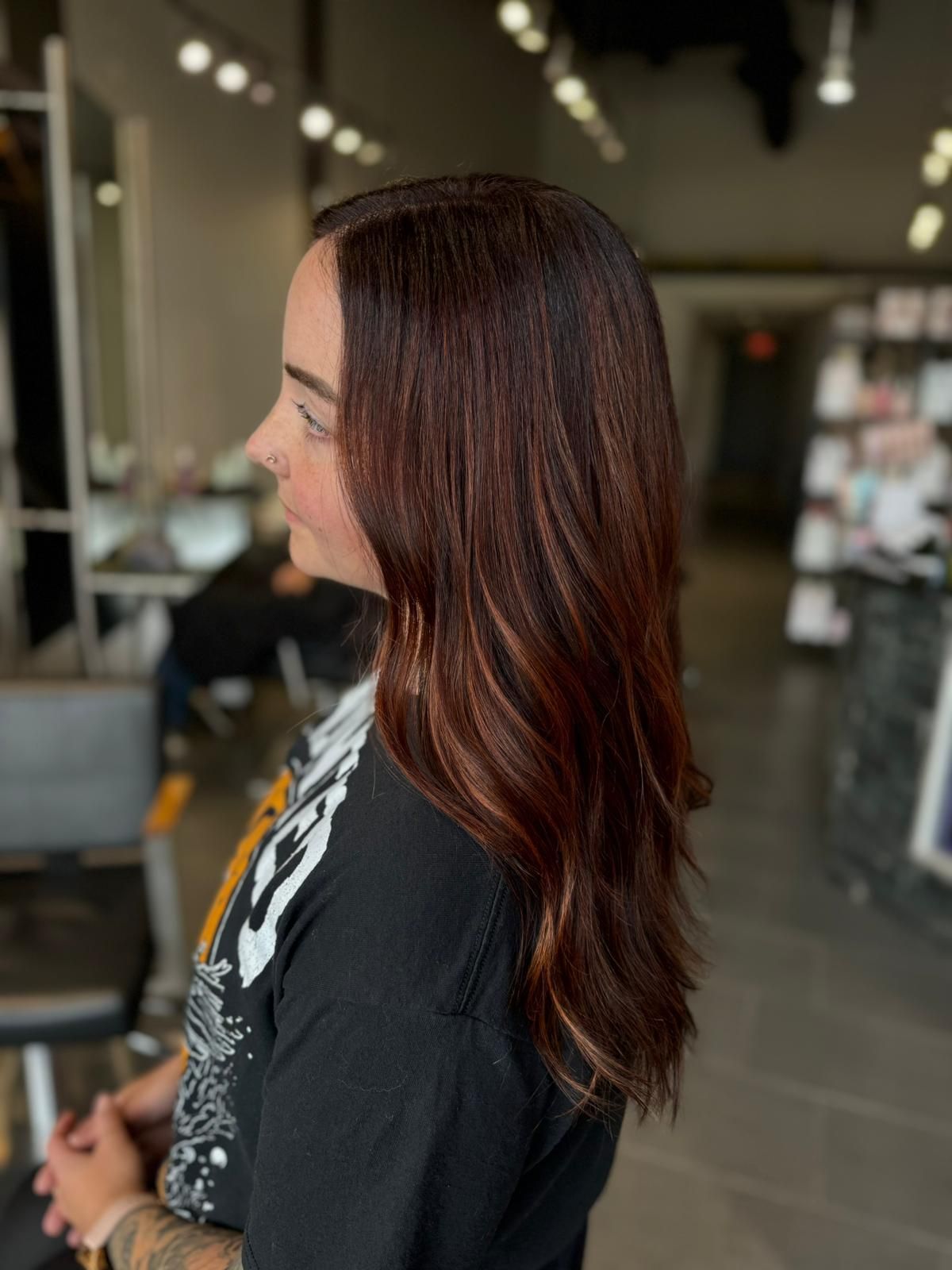 A woman with long brown hair is standing in a salon.