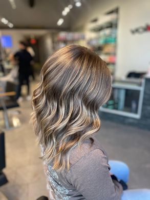 A woman is sitting in a chair with her hair in a salon.