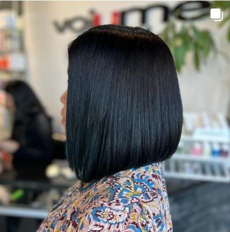 a woman with black hair is wearing a floral shirt and a bob hairstyle .