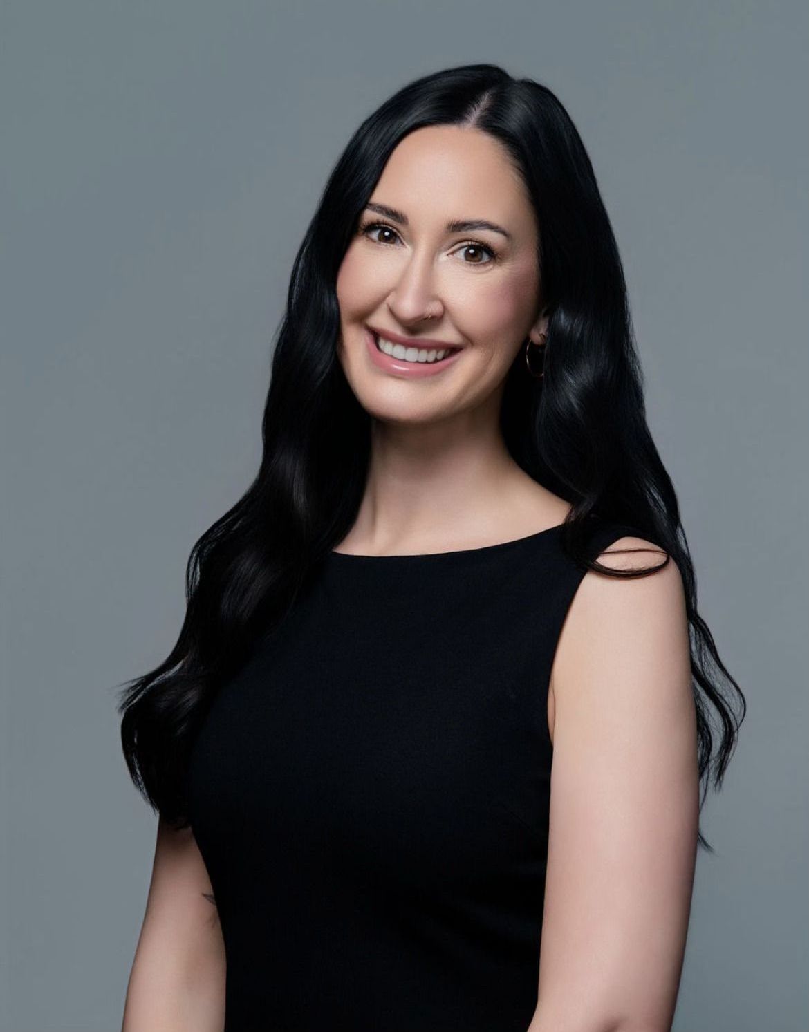 The woman is wearing a black dress and smiling for the camera.