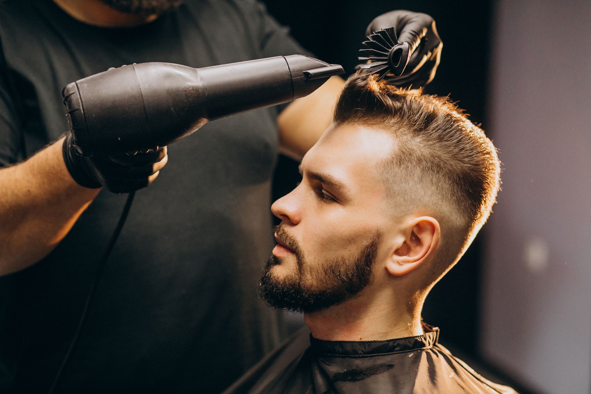 a man is getting his hair blow dried by a barber .