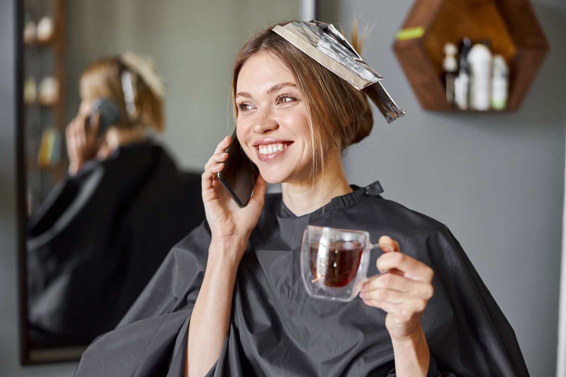 a woman is talking on a cell phone while holding a cup of coffee .