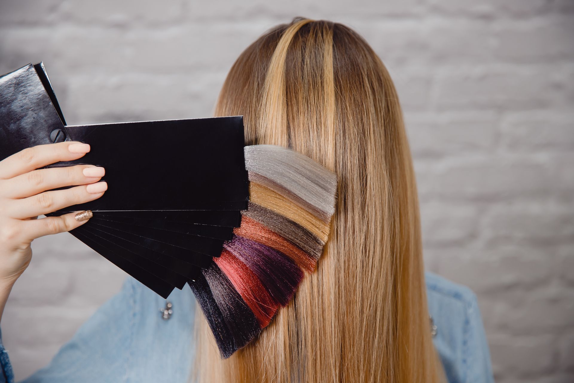 a woman is holding a palette of hair colors in front of her hair .