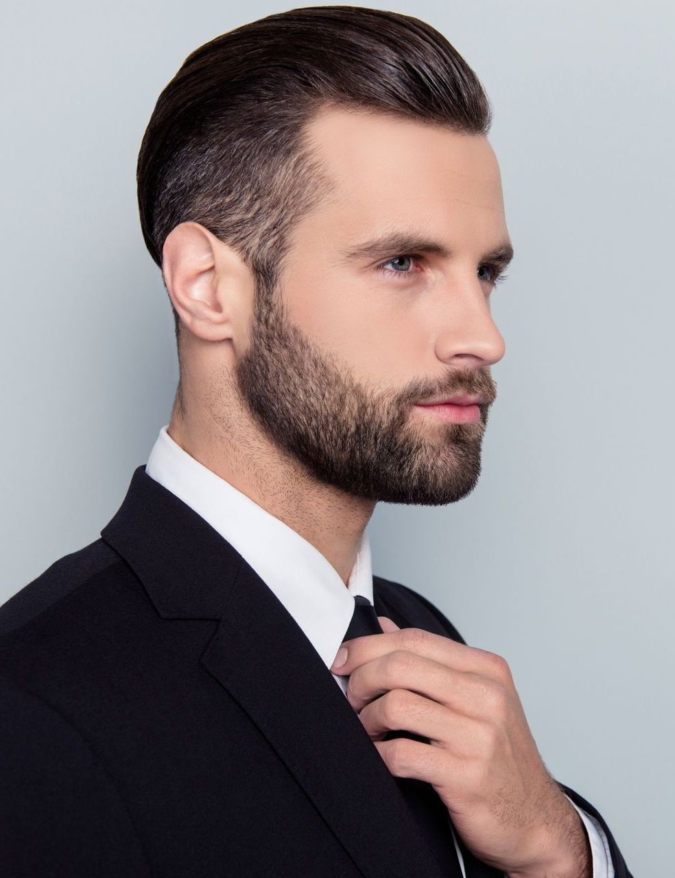 a man in a suit and tie is adjusting his tie .