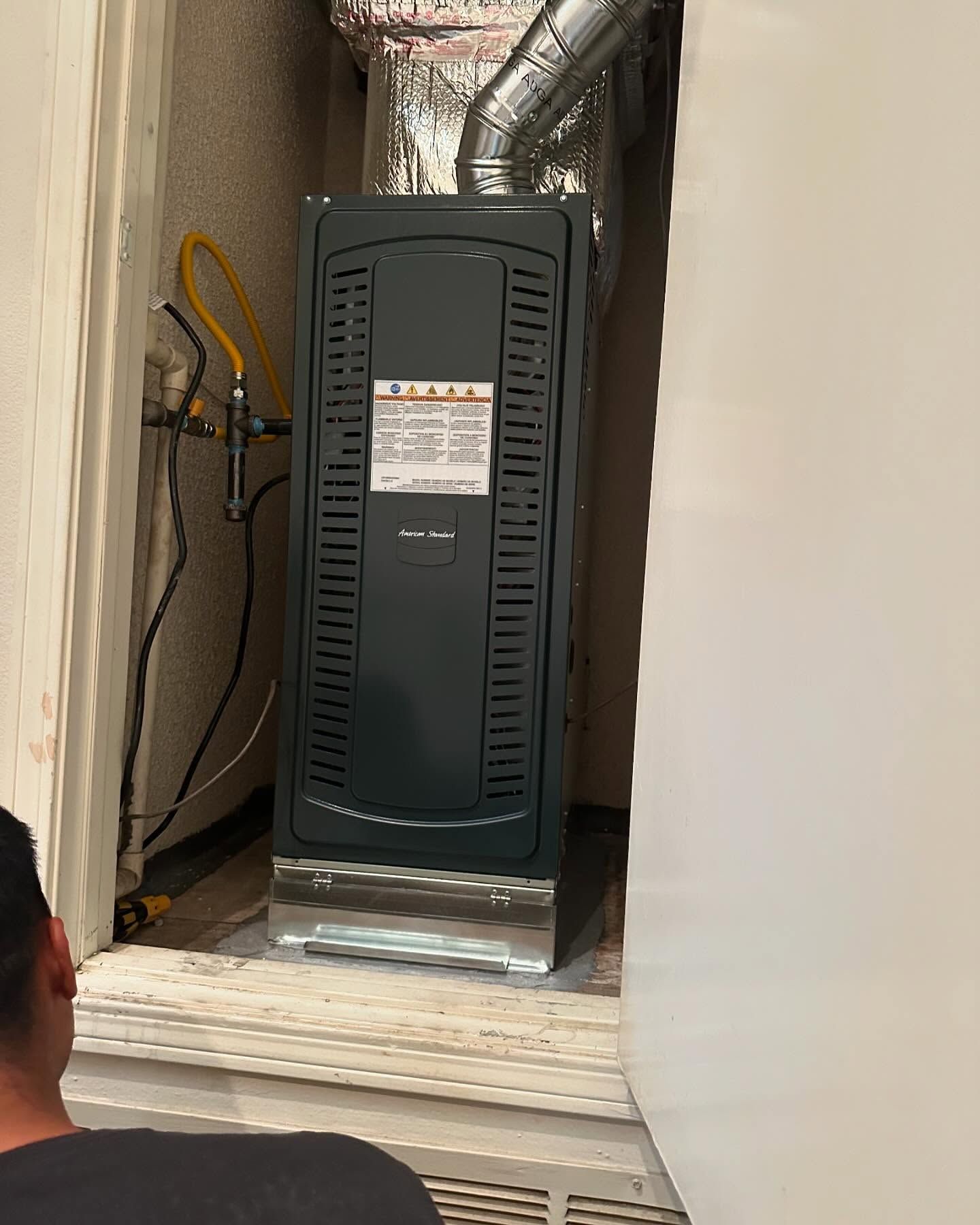 Tip of the Spear HVAC | a man is looking at an air conditioner in a room.