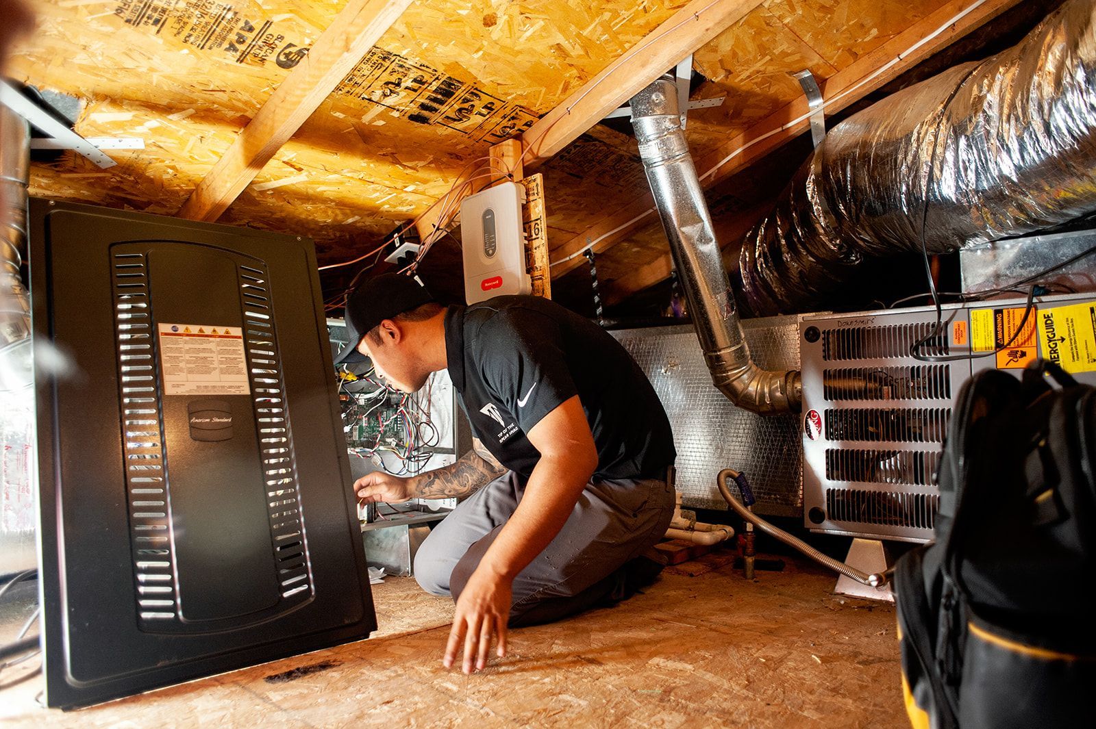 A person inspecting HVAC equipment in an attic.