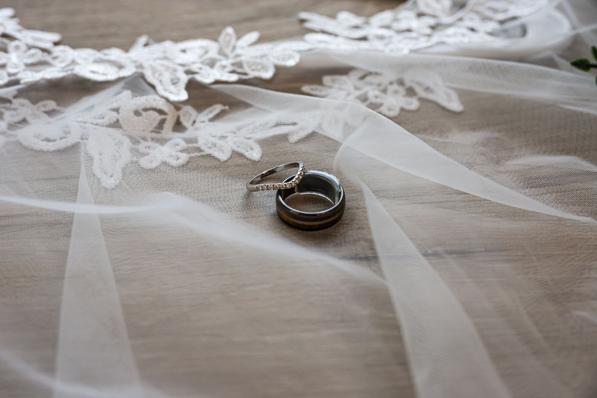 Wedding rings on a white veil with lace detailing.