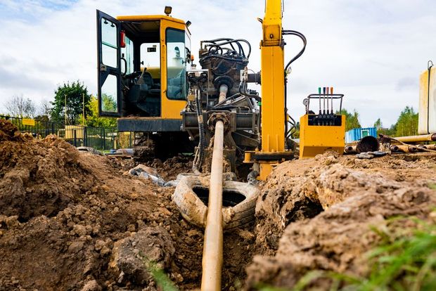 Utility drilling machine installing an underground pipe in a muddy trench
