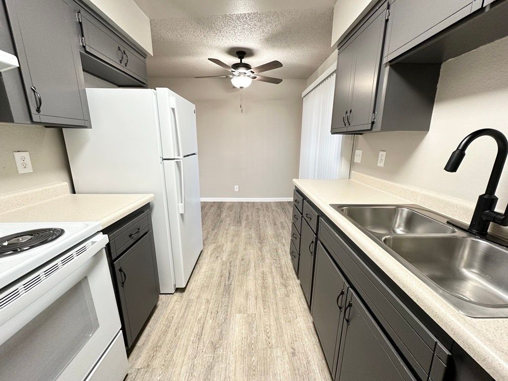 Kitchen with grey cabinets, white appliances, and light wood floors.