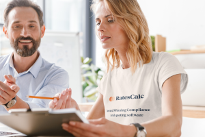 professional woman in a RatesCalc tshirt assisting a businessman, using a clipboard