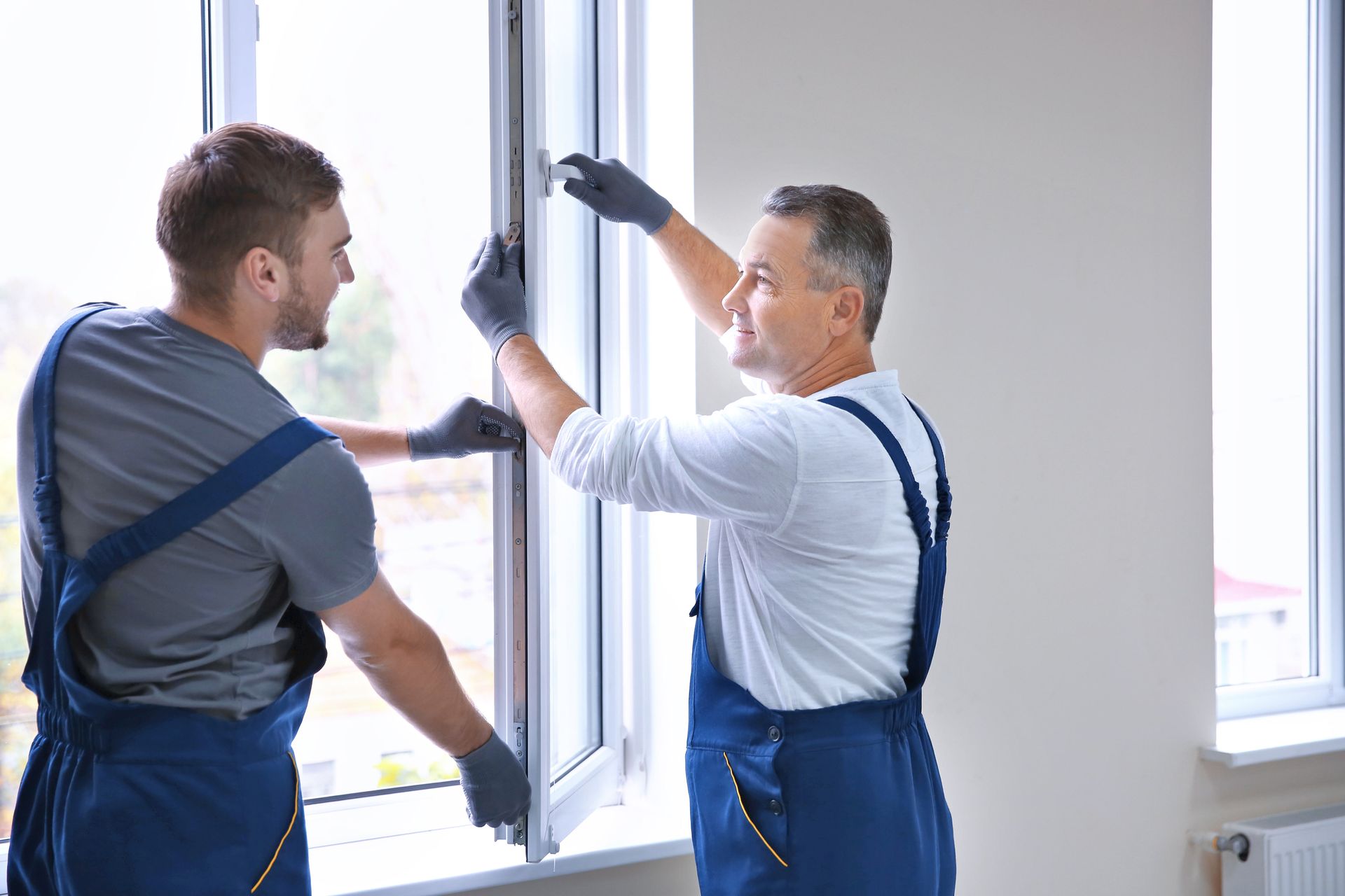Workers from a window installation company installing a window in a house. Workers from a window installation company installing a window in a house.