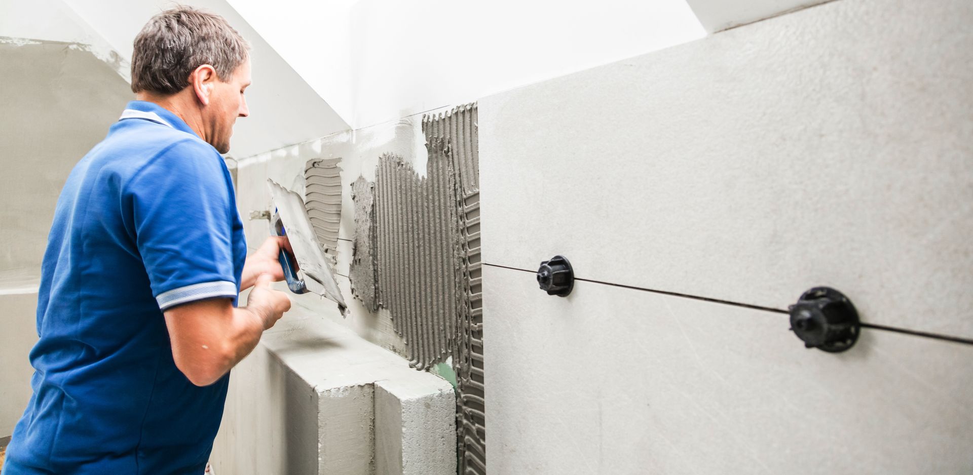 Professional installer applying adhesive for a custom bathroom remodeling services tile installation.