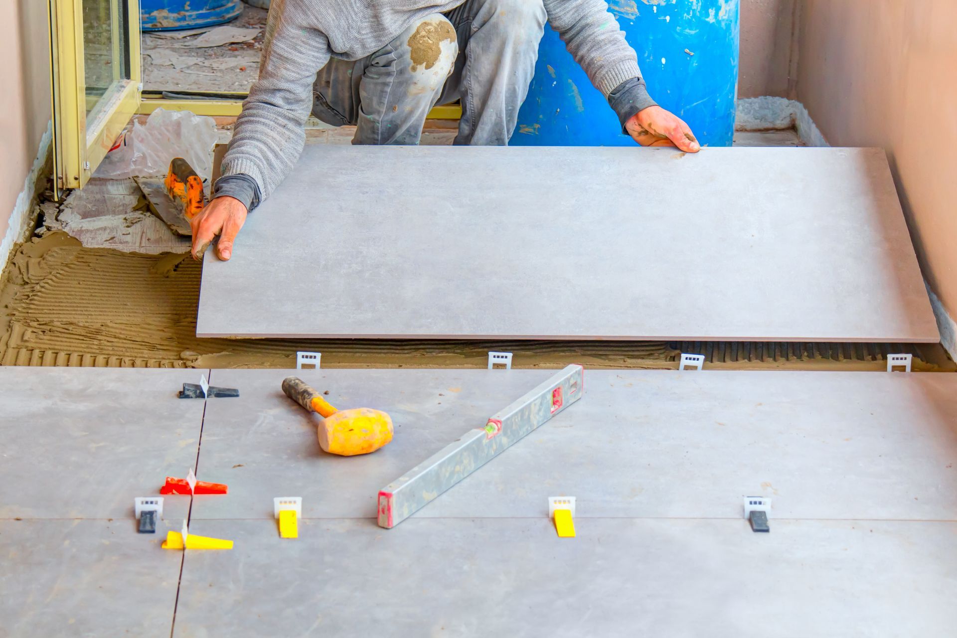 Installation of large-format bathroom tile with leveling clips during a bathroom remodeling project.