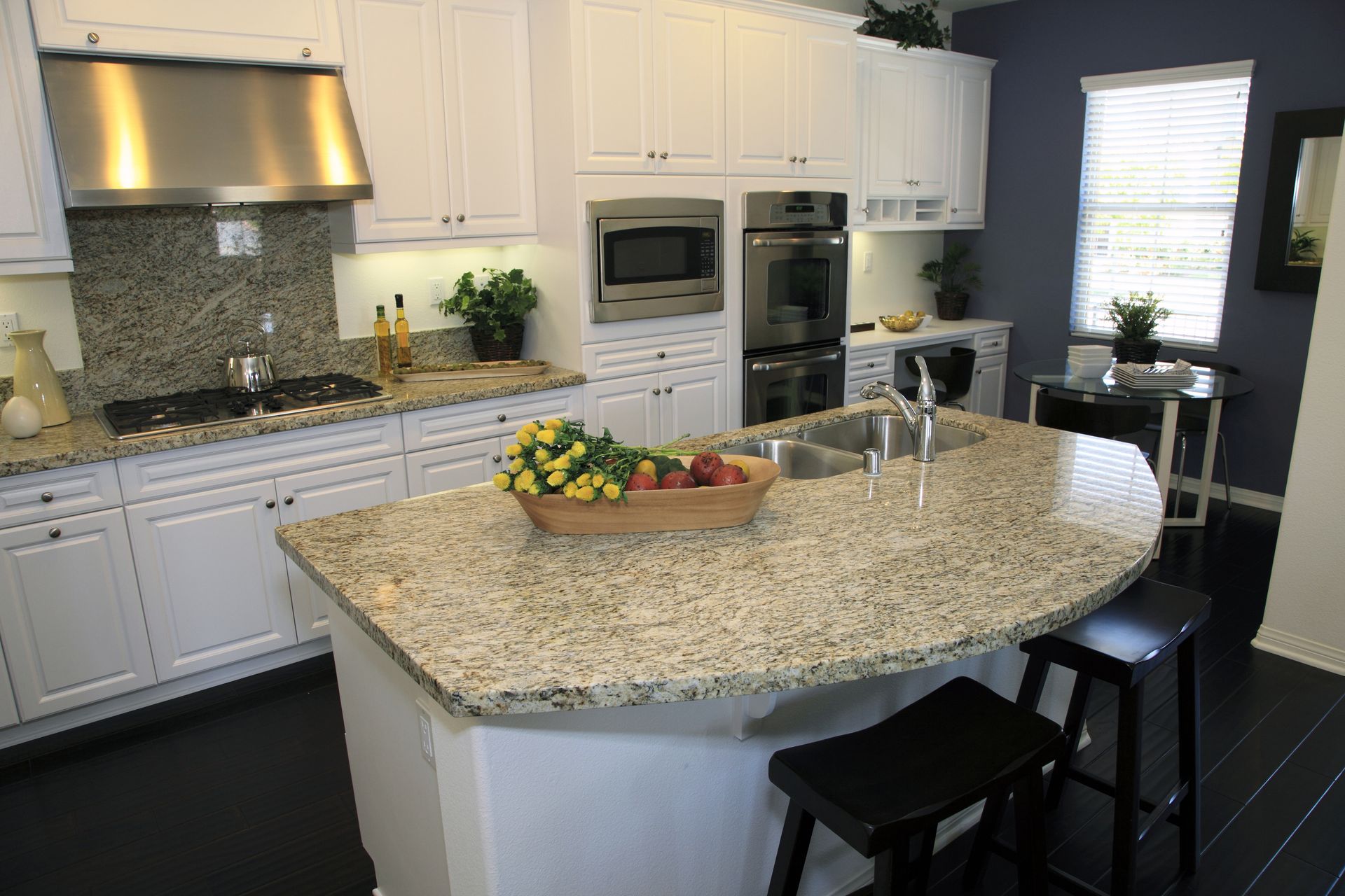 White kitchen with granite countertops, stainless steel appliances, and a breakfast bar.