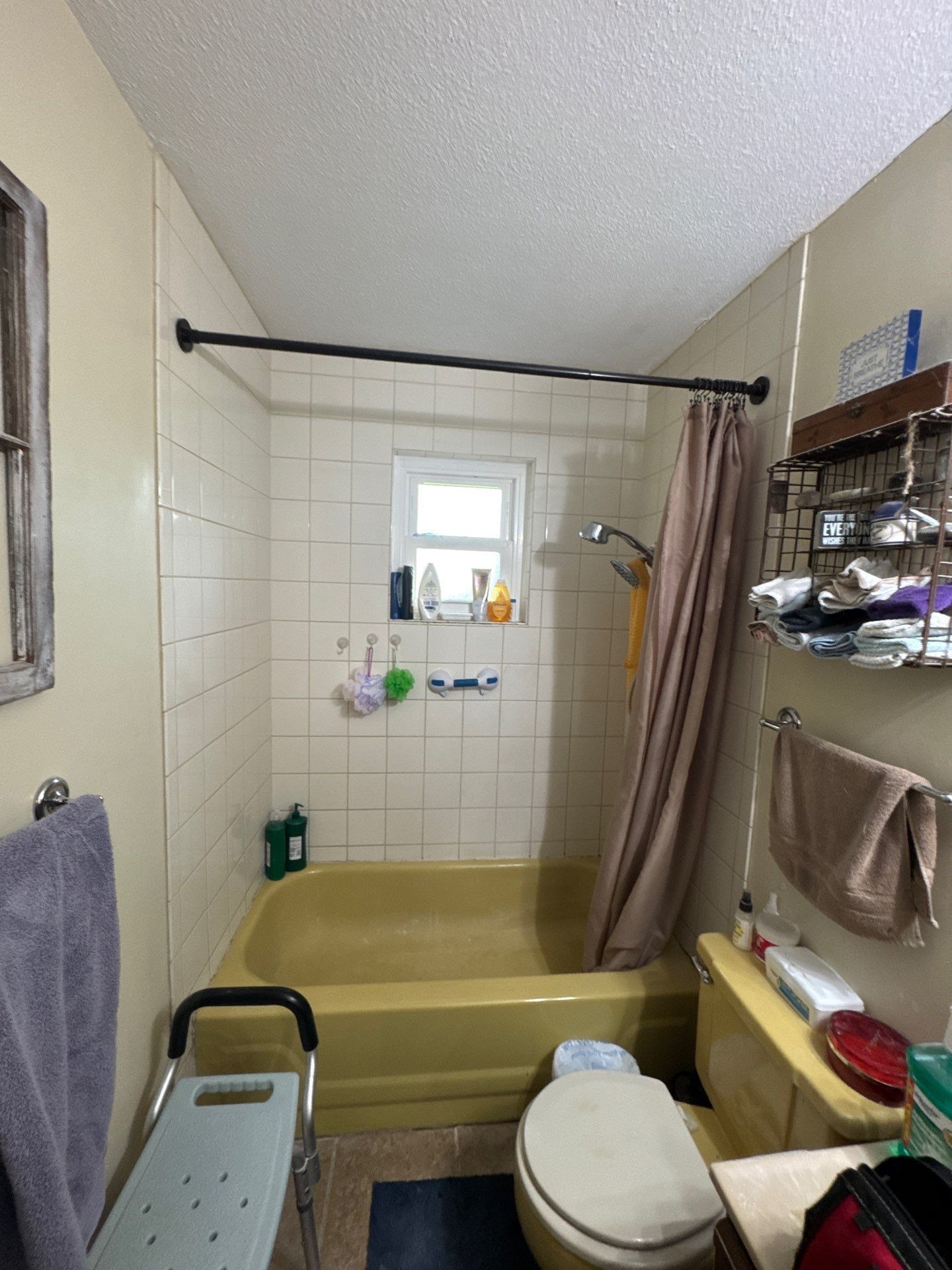 A small, cluttered bathroom with a yellow bathtub