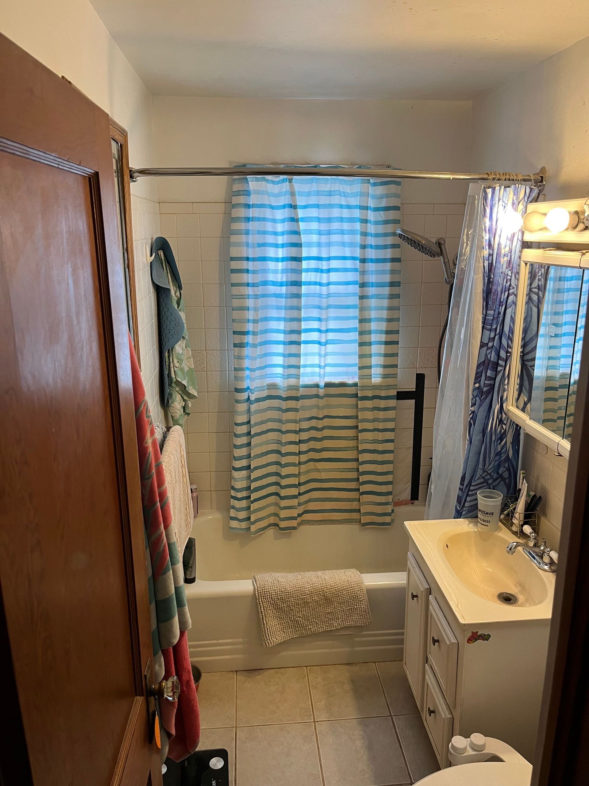 A small bathroom with a bathtub, shower curtain, and a single sink vanity.