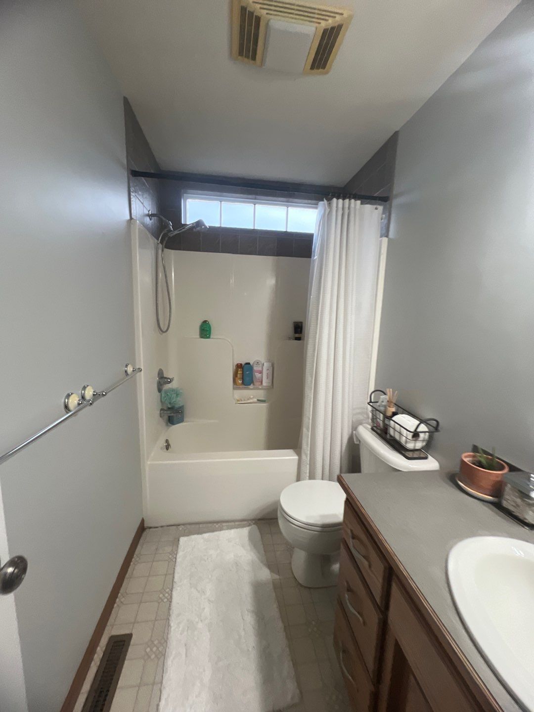 Gray bathroom with a white bathtub, shower, toilet, and wooden vanity