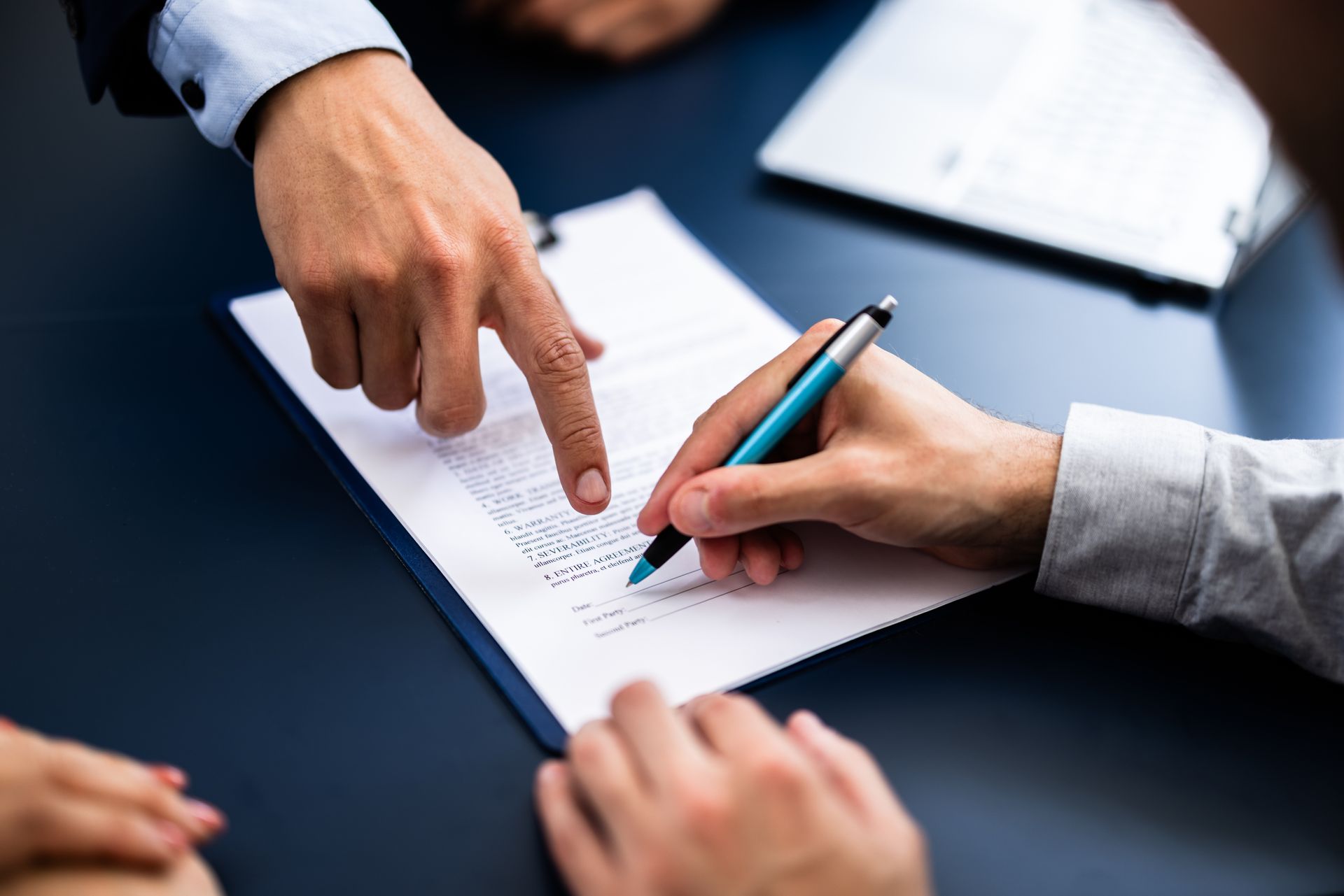 A man is pointing at a person signing a document.