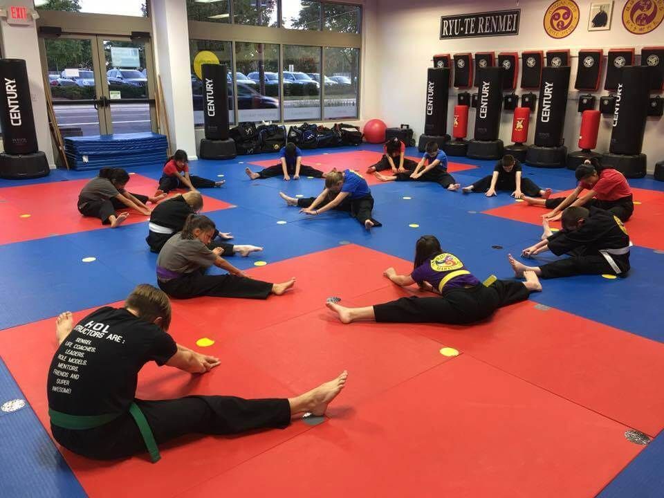 A group of people are doing stretching exercises in a gym.
