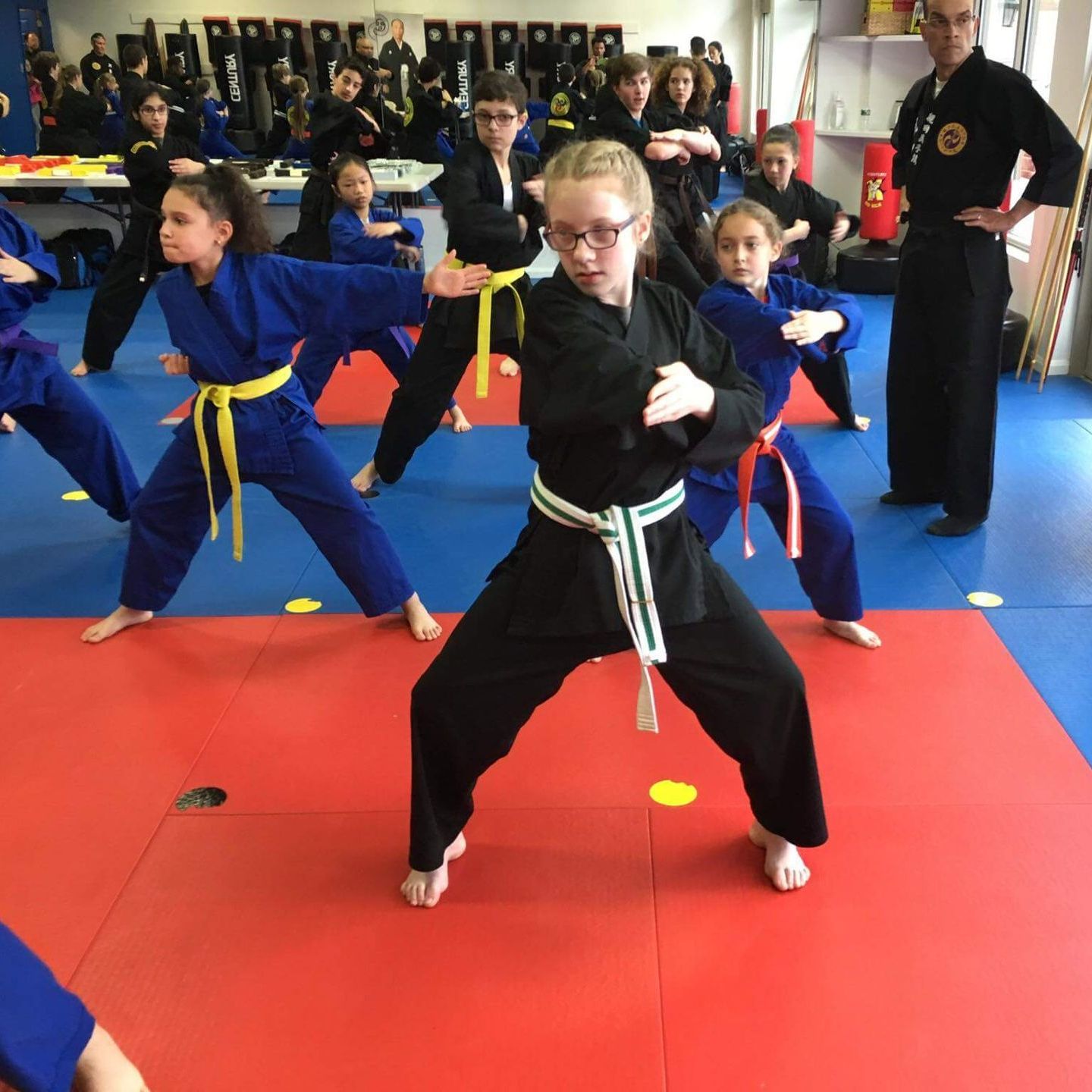 A group of kids are practicing martial arts in a gym
