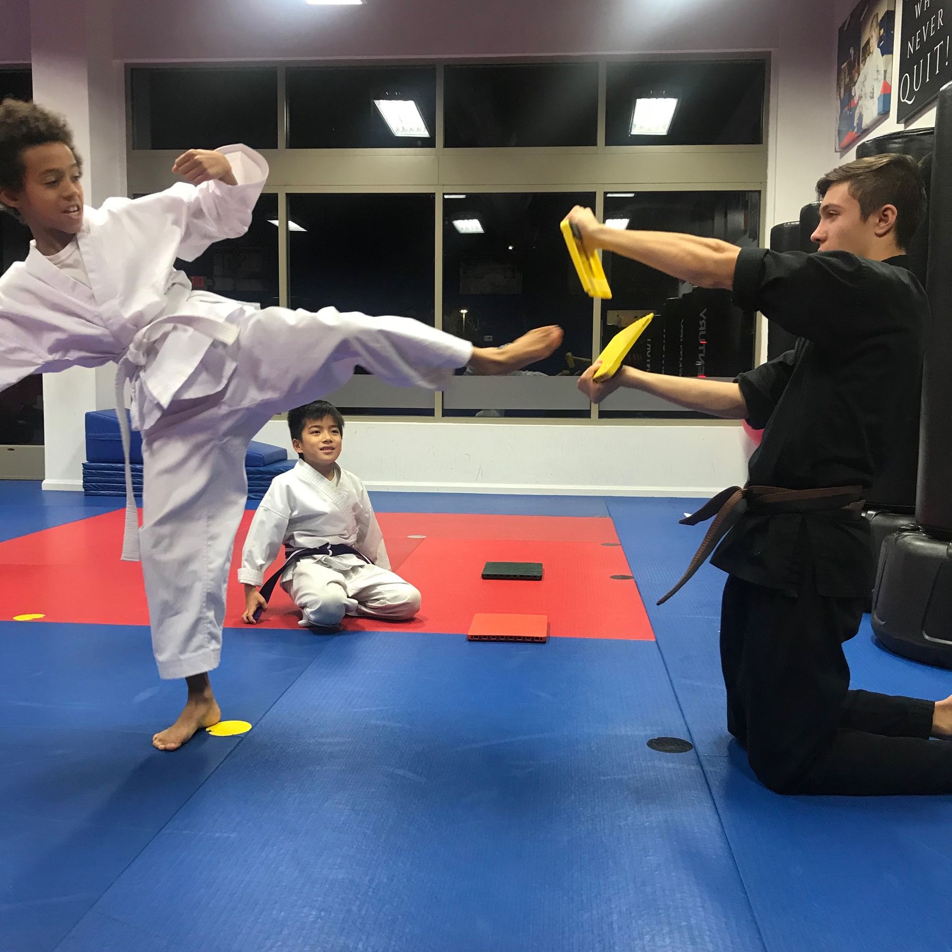 A boy in a white karate uniform kicks a yellow object