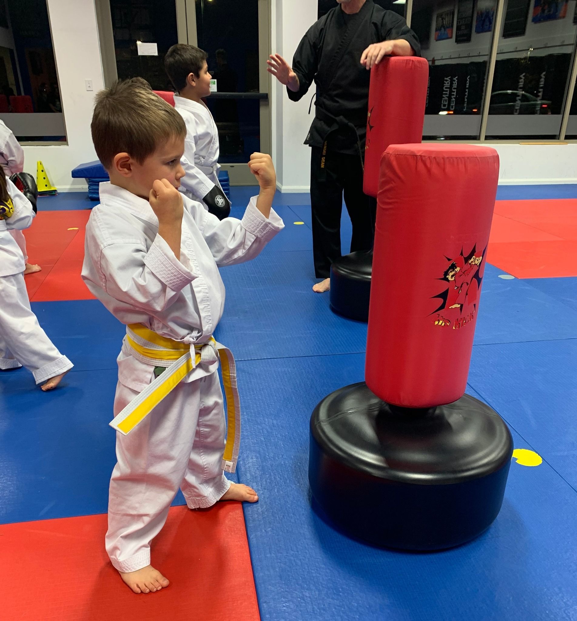 A group of young boys are practicing martial arts in a gym.
