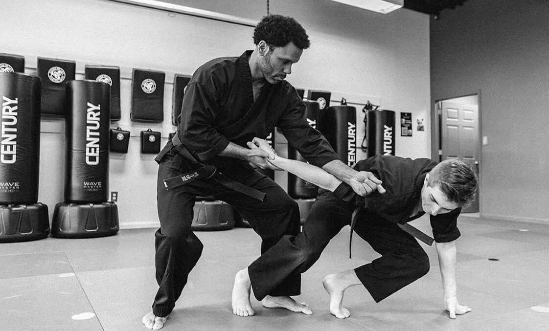 A black and white photo of two men practicing martial arts in a gym.