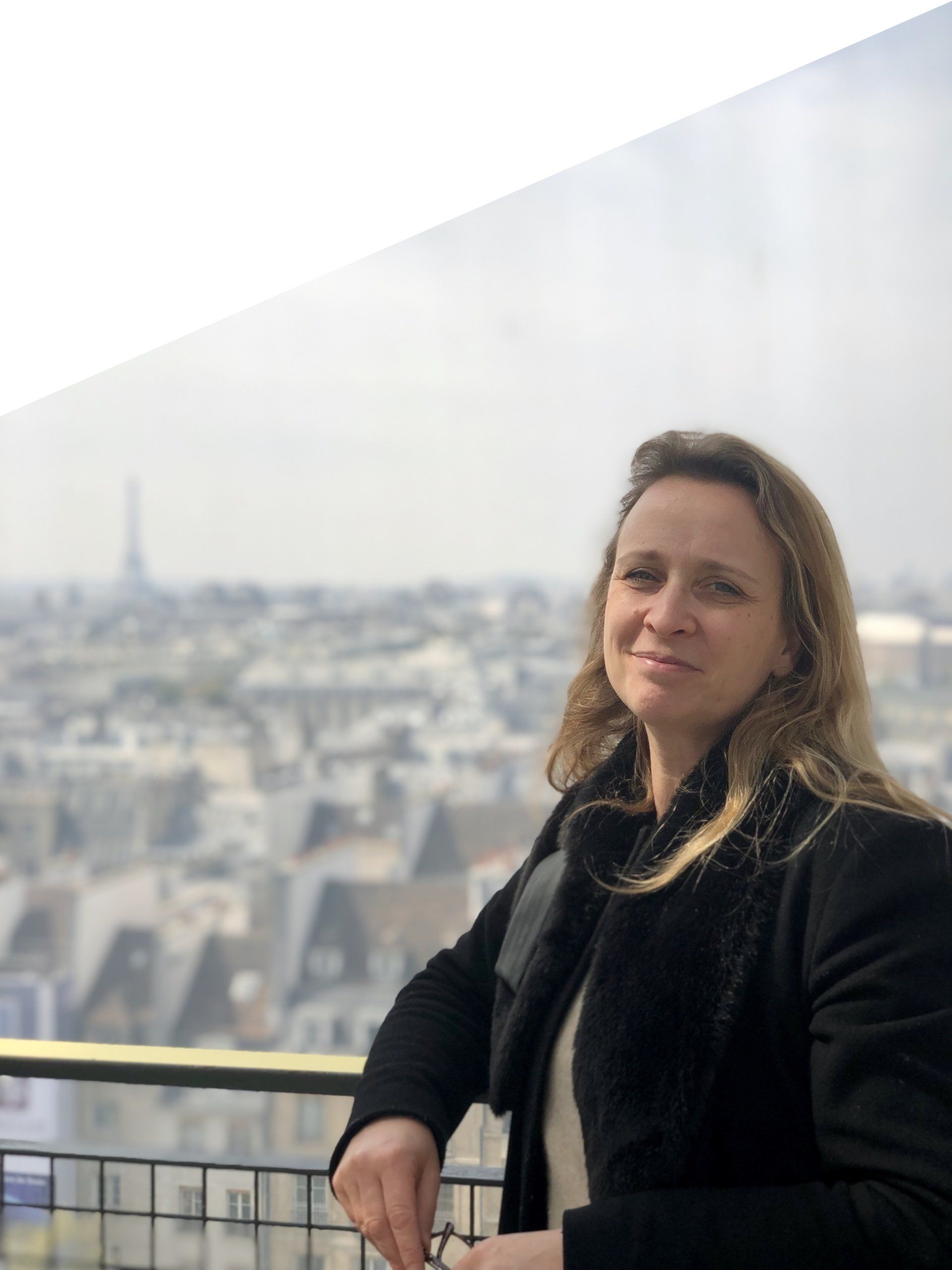 Une femme se tient debout sur un balcon surplombant une ville.
