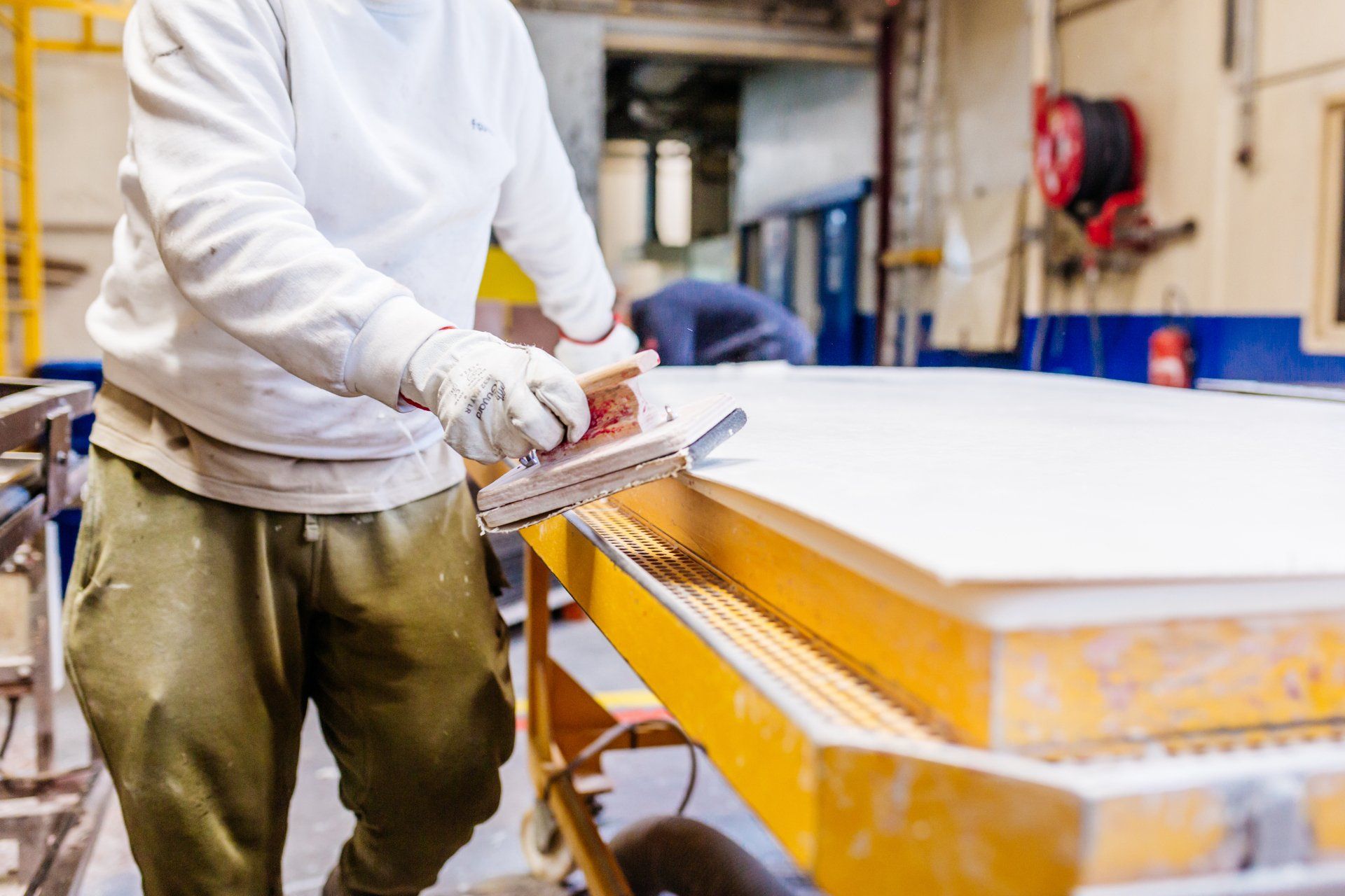 Un homme ponce un morceau de bois dans une usine.