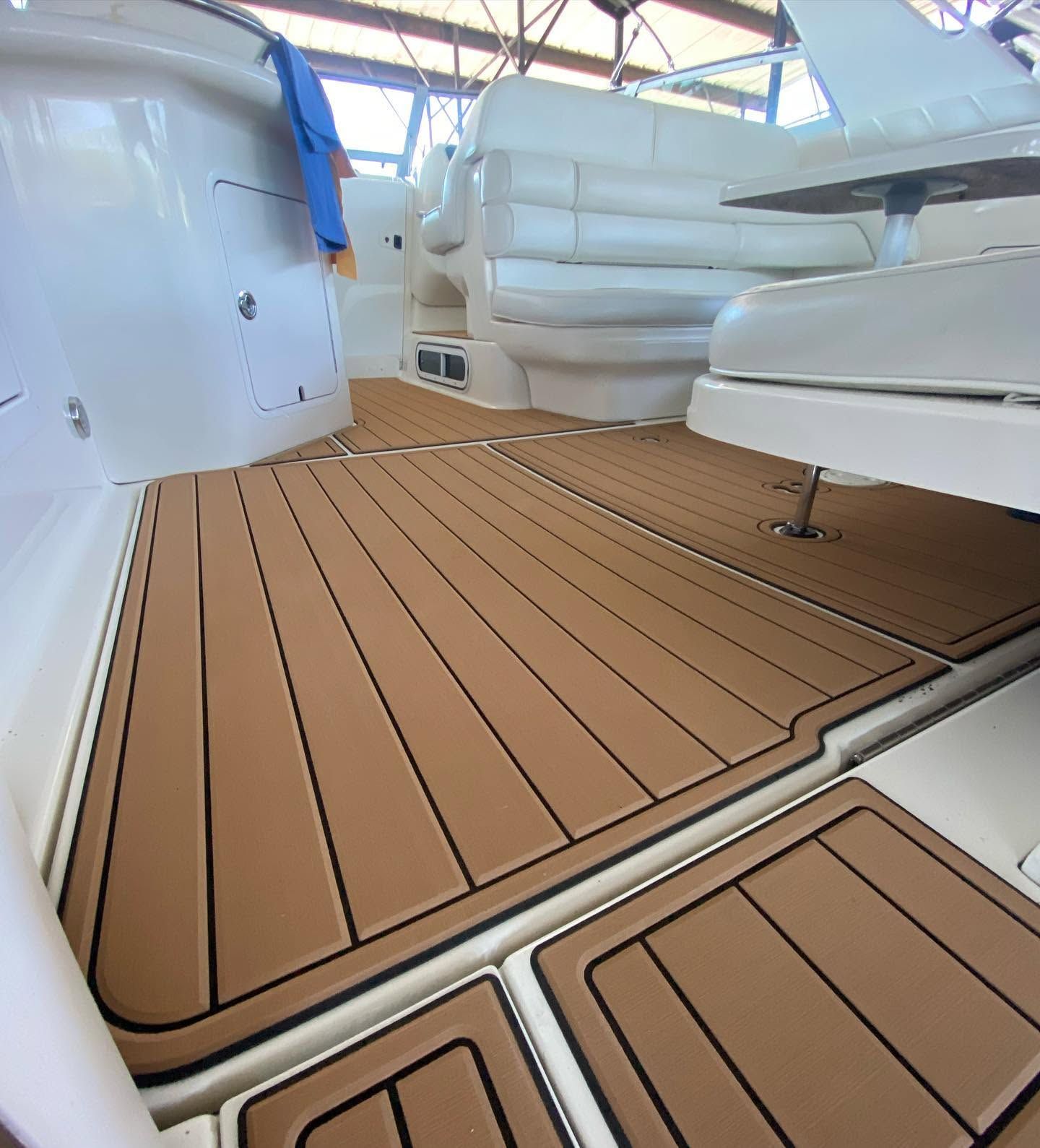 Yacht deck with tan wood-look flooring and white cushioned seating in a bright cabin area