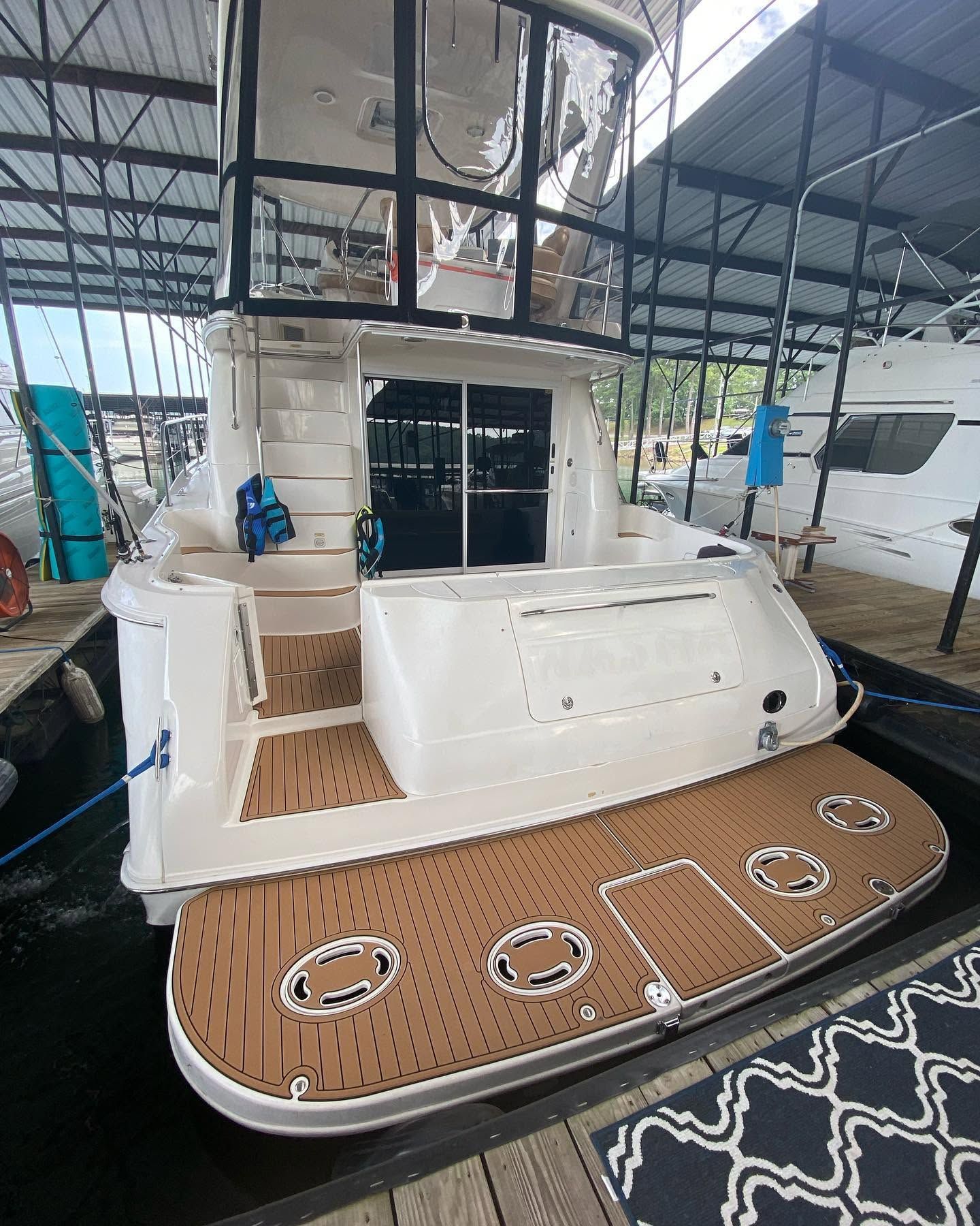 White yacht stern with wood-style swim platform in a covered marina