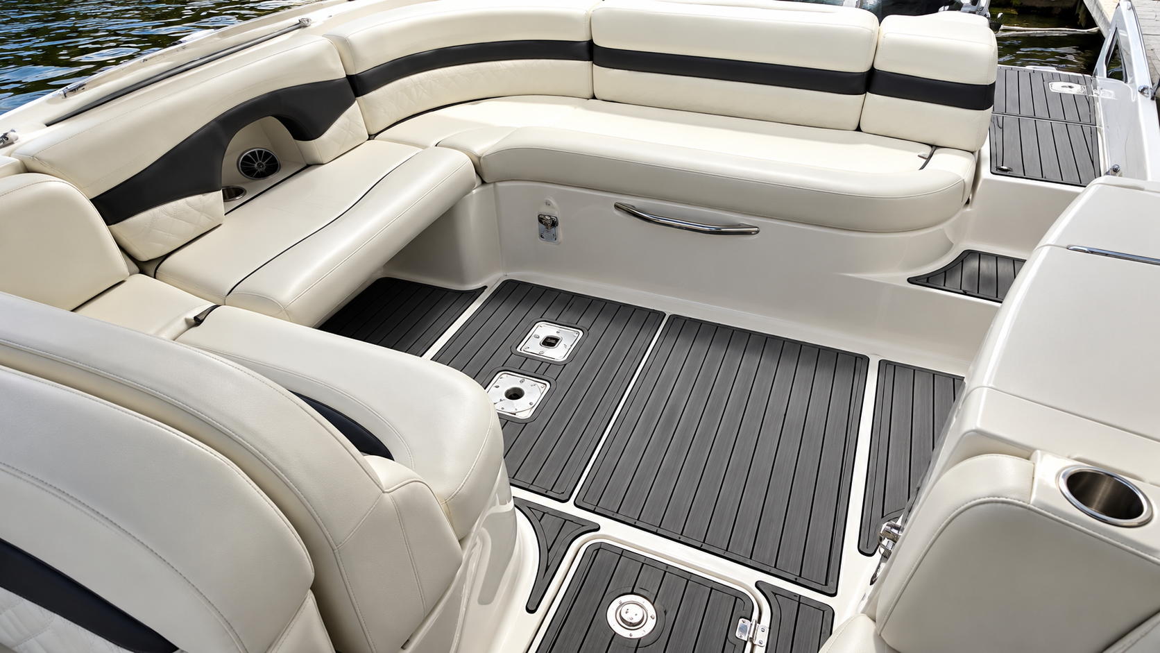 Cream and black upholstered boat seating around a gray deck in a sunlit cabin area