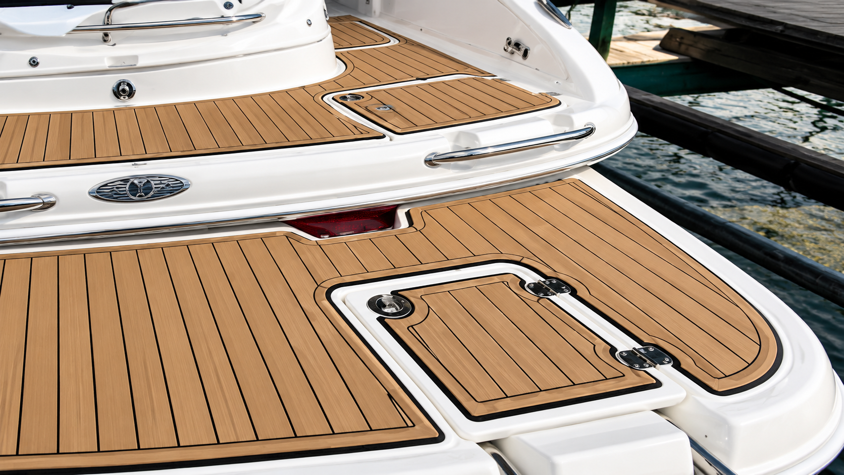 Boat stern with teak decking and a small hatch beside the water at a marina
