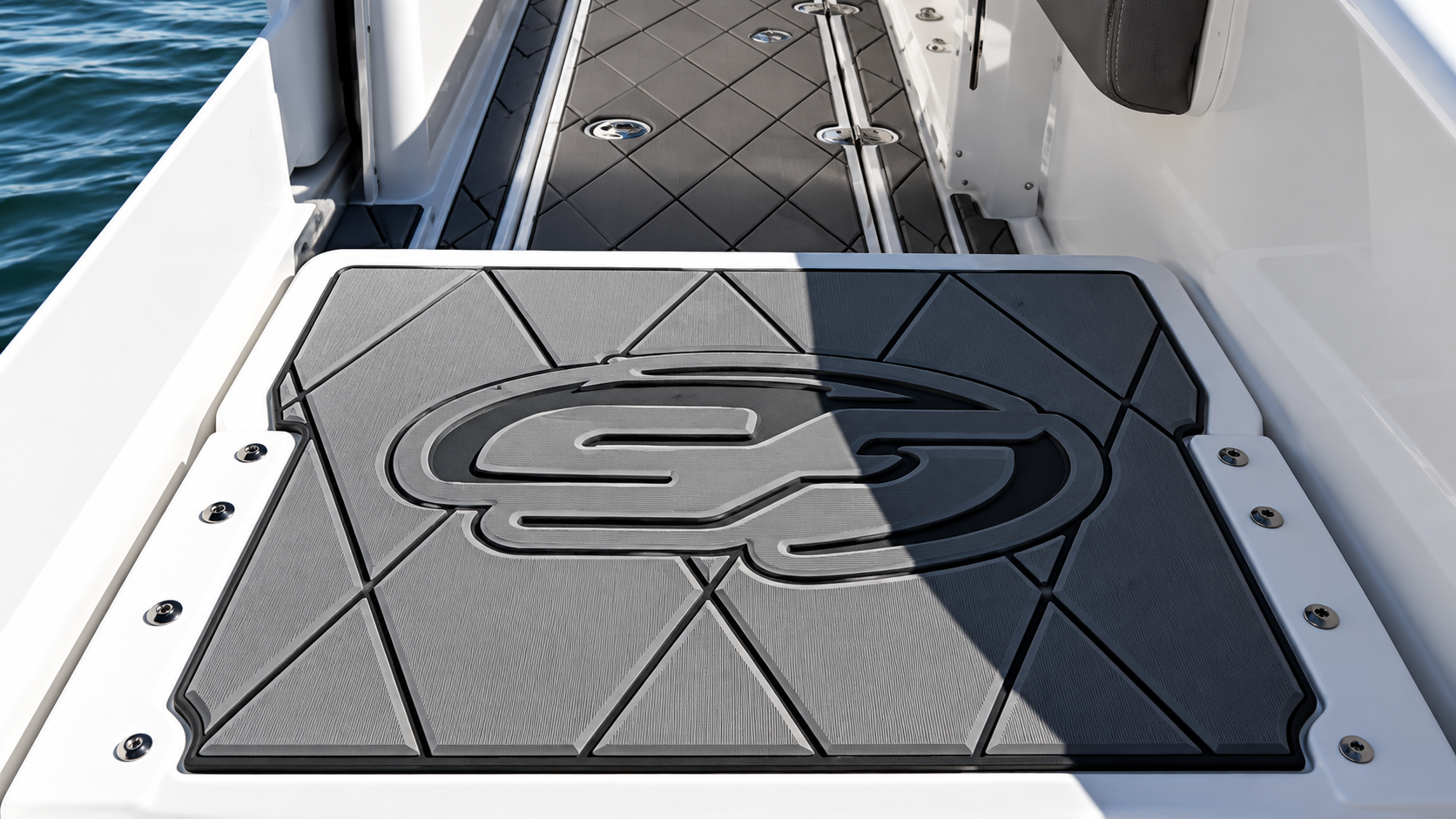 Gray embossed logo on a black textured panel mounted on a boat deck beside railing and water