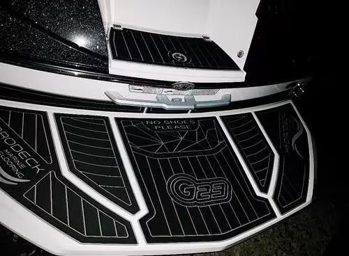 Close-up of a black-and-white off-road vehicle front grille with metal mesh and hood vent at night