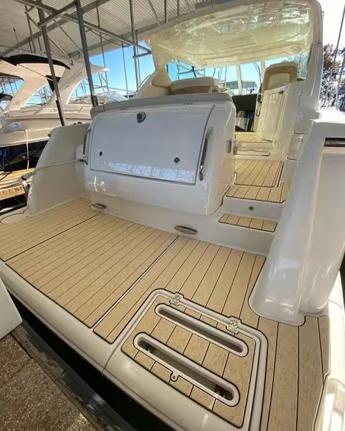 Boat stern with tan decking, white seating, and an open swim platform under a canopy.