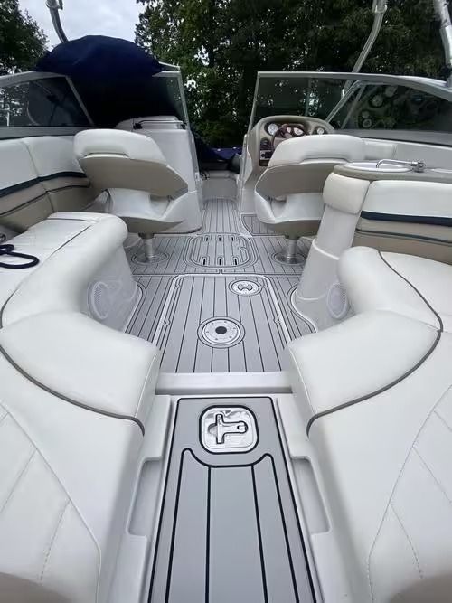 Boat interior with white seats and striped deck, viewed from the stern toward the helm under a canopy.