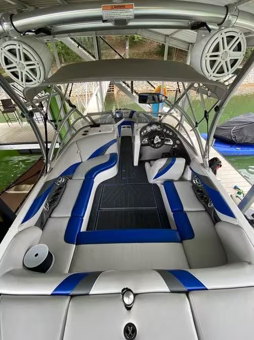 Boat interior with white and blue seating, under a wakeboard tower, seen from the stern