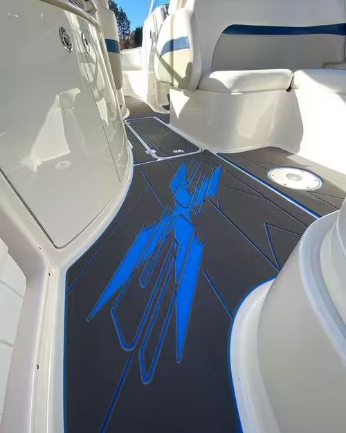 Boat deck with blue and black geometric flooring between white seats and console.