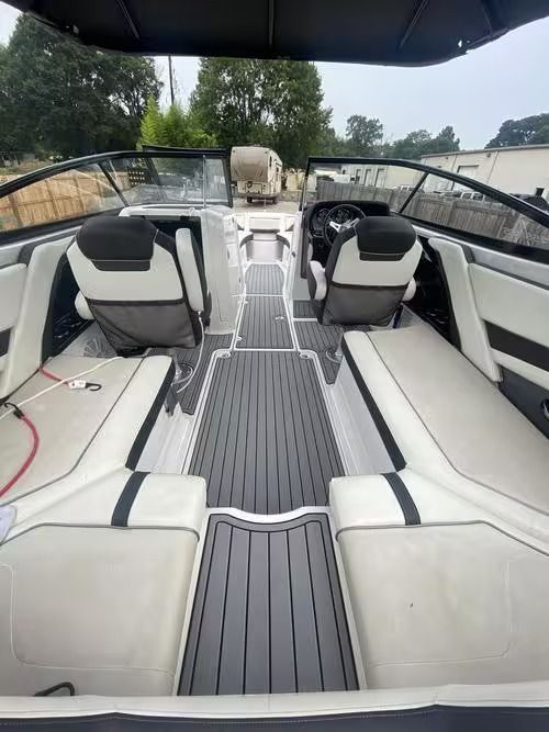 Boat cabin interior with white and black seats, gray flooring, and open windshield view on the water