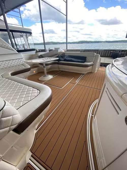 Luxury yacht deck with white cushioned seating, teak flooring, and ocean view under cloudy sky