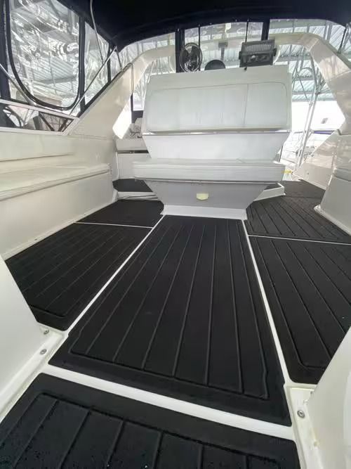 White boat cabin with black flooring and upholstered bench seats, viewed from the center aisle