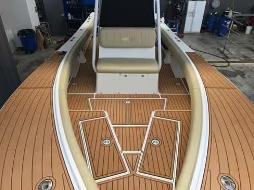 White-and-wood boat deck with tan seating, seen from the bow in a marina.