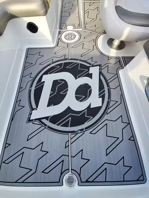 Gray boat deck mat with a large Dd logo and star pattern between seats and fixtures.