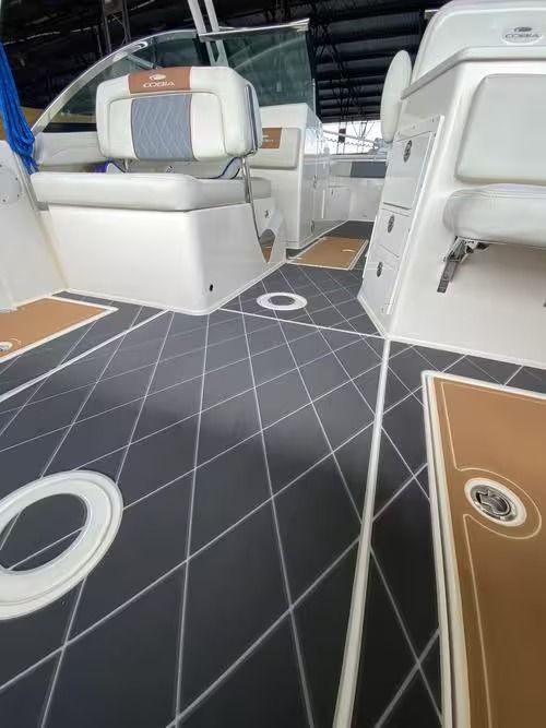 Boat cockpit with white cushioned seats and black diamond-pattern deck flooring.