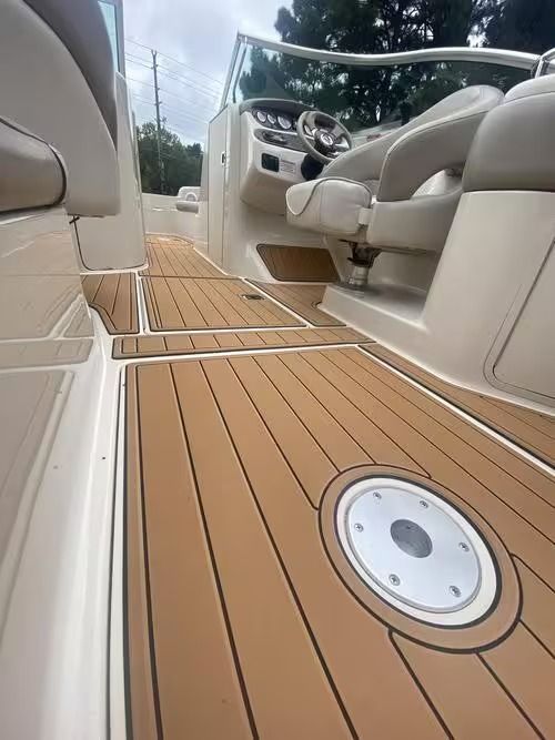 Boat cockpit with tan cushioned seats and wood-look deck flooring, viewed toward the steering console.