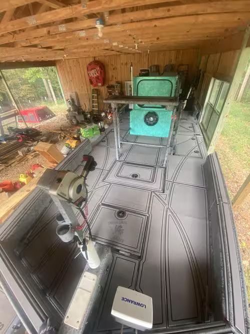 Wood-paneled workshop with a patterned floor, tools on the left, and a turquoise machine at the far end.
