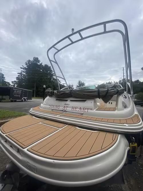 Boat deck with tan teak flooring and white railings, viewed from the stern under an overcast sky