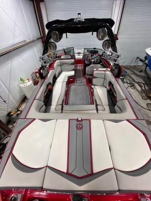 Customized boat interior with white, red, and gray upholstery in a garage or workshop.