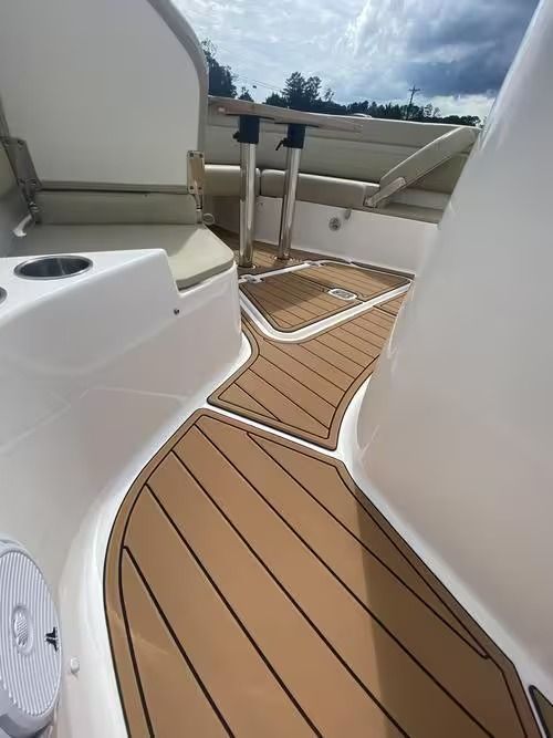 Narrow boat deck with tan non-slip flooring, white railings, and a small table on a cloudy day